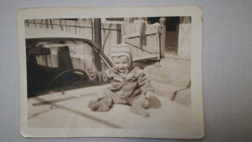 Fotografie de arhivă alb-negru: un copil pe capota unei Dacii 1310